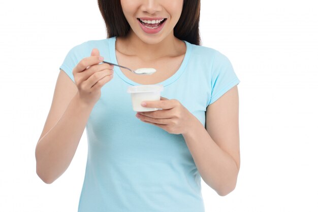 Mujer sonriente que come el yogur