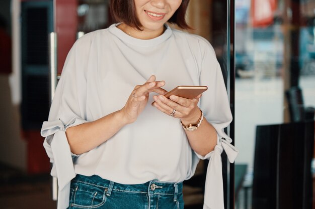 Mujer sonriente que controla smartphone