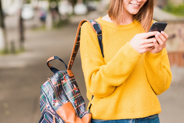 Mujer sonriente que controla su teléfono