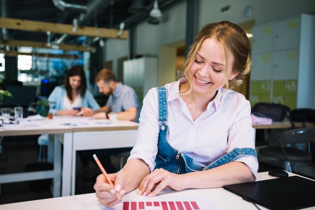 Foto gratuita mujer sonriente que corrige el gráfico