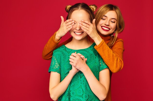 Mujer sonriente que cubre los ojos con las manos a su amiga