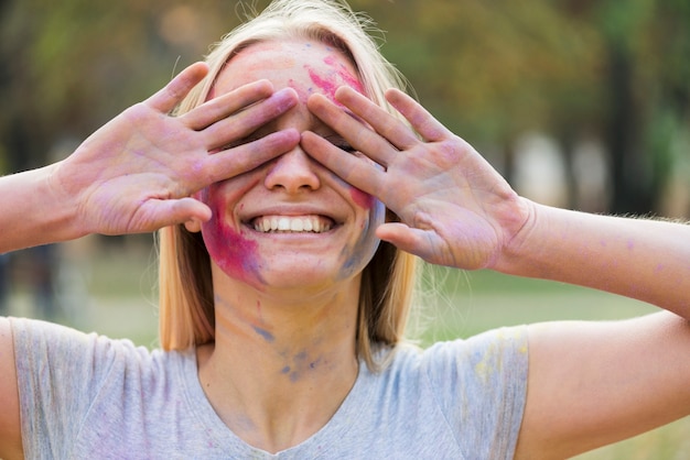 Mujer sonriente que cubre sus ojos en el festival