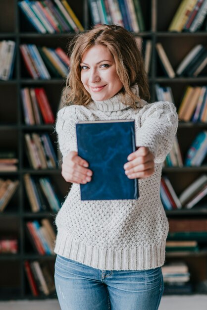 Mujer sonriente que demuestra el libro