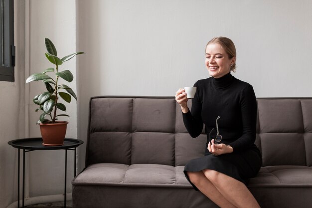 Mujer sonriente que goza de la taza de café