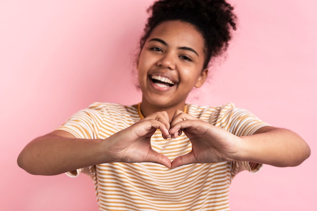 Mujer sonriente que hace forma del corazón con las manos