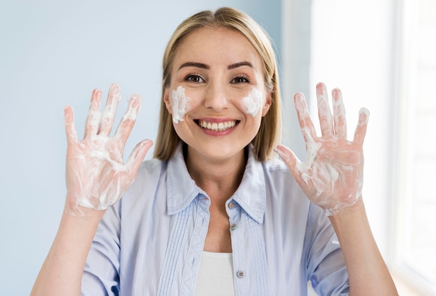 Mujer sonriente que se lava las manos con jabón