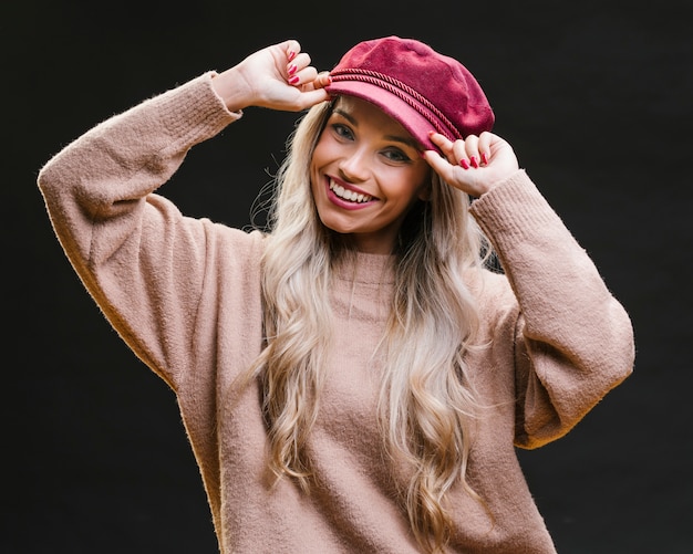 Mujer sonriente que lleva el casquillo rosado y que presenta contra fondo negro