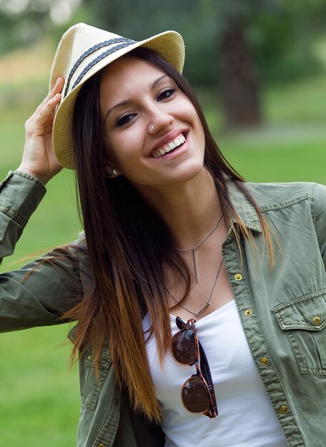 Mujer sonriente que lleva el sombrero en el parque