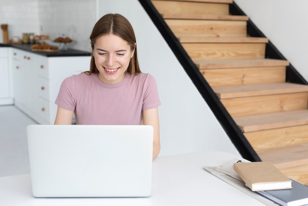 Mujer sonriente que mira en su computadora portátil