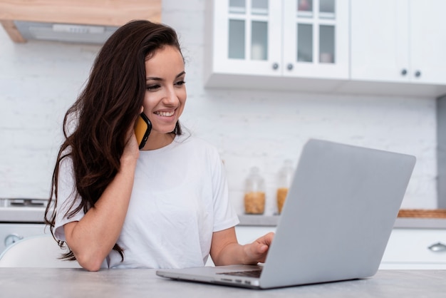 Mujer sonriente que mira en su computadora portátil