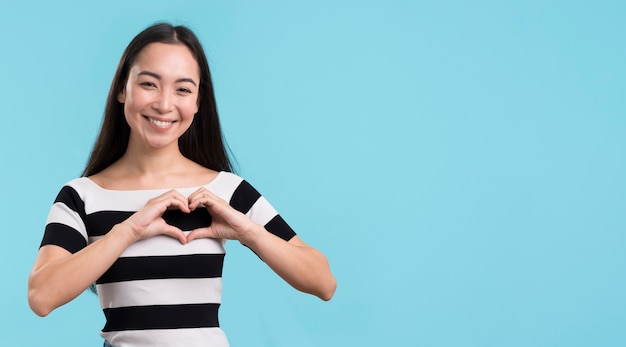 Mujer sonriente que muestra forma del corazón