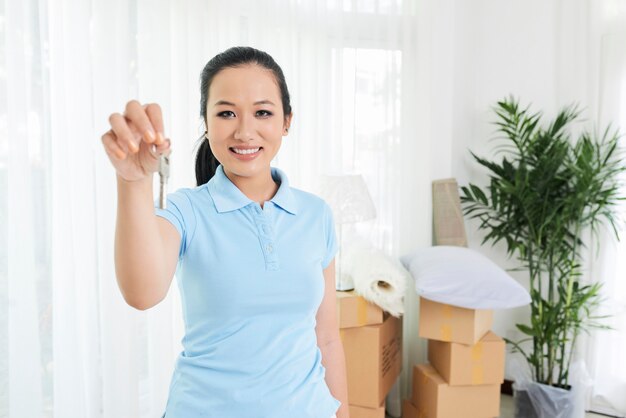 Mujer sonriente que muestra la llave del apartamento nuevo