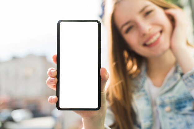 Mujer sonriente que muestra la pantalla en blanco del teléfono inteligente