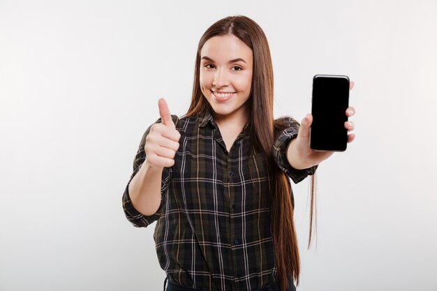 Mujer sonriente que muestra la pantalla del teléfono inteligente en blanco