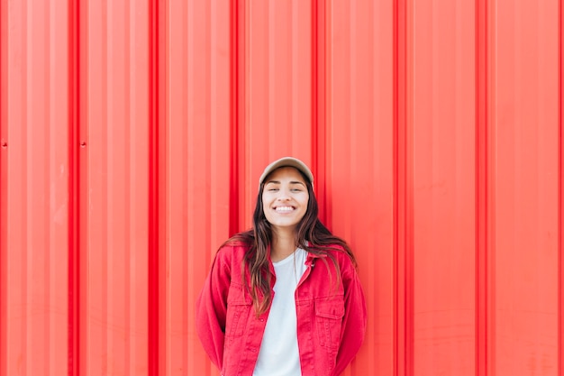 Foto gratuita mujer sonriente que se opone a fondo acanalado rojo