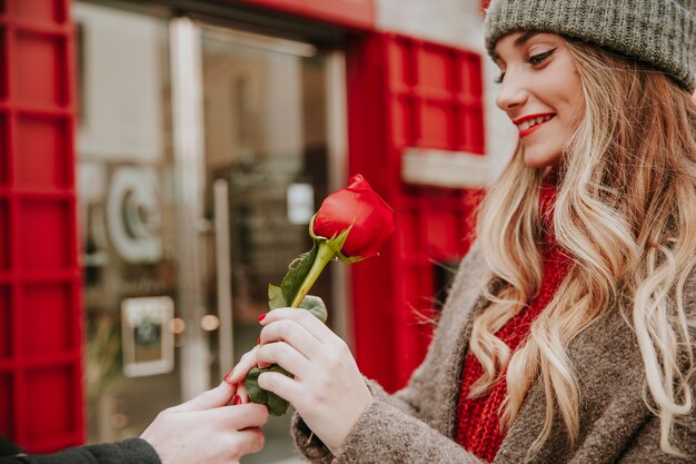 Mujer sonriente que recibe la rosa roja