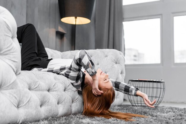 Mujer sonriente que se relaja en el sofá