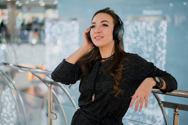 Foto gratuita mujer sonriente que sostiene los auriculares en la cabeza en el centro comercial