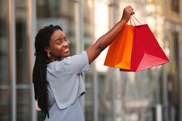 Mujer sonriente que sostiene bolsos de compras