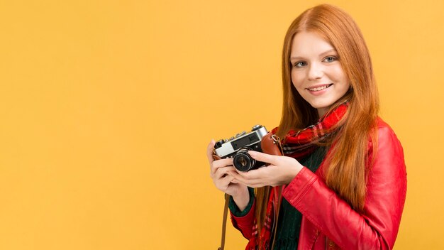 Mujer sonriente que sostiene la cámara de fotos