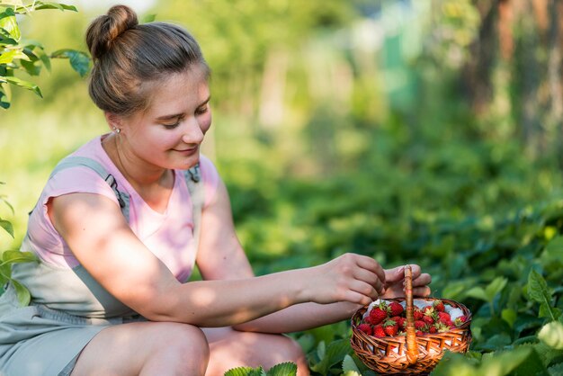 Mujer sonriente que sostiene la cesta de frutas