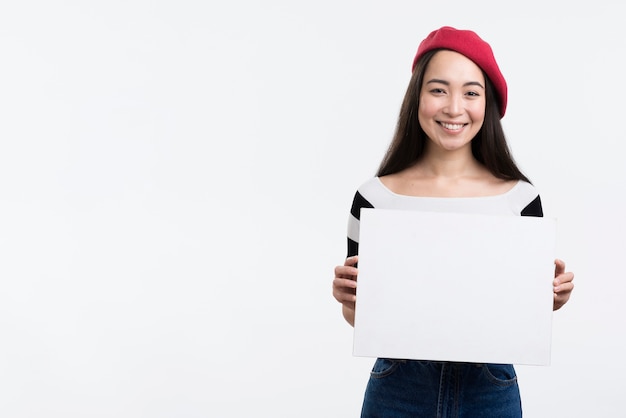 Foto gratuita mujer sonriente que sostiene la hoja de papel en blanco