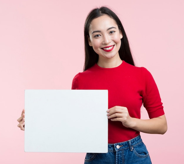 Mujer sonriente que sostiene la hoja de papel en blanco