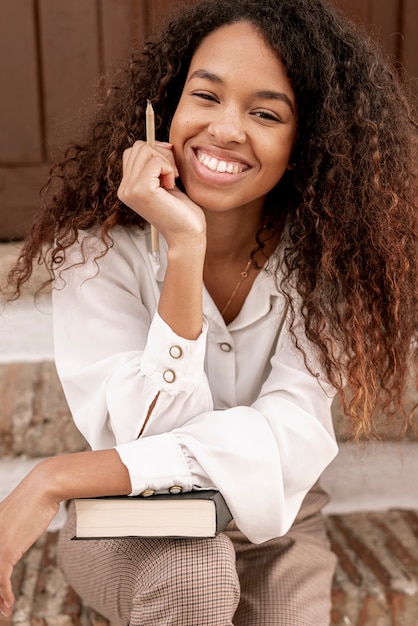 Mujer sonriente que sostiene un libro