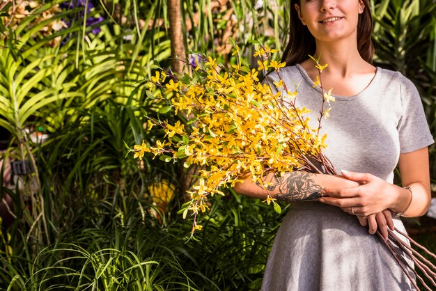 Mujer sonriente que sostiene el manojo de ramitas de la planta