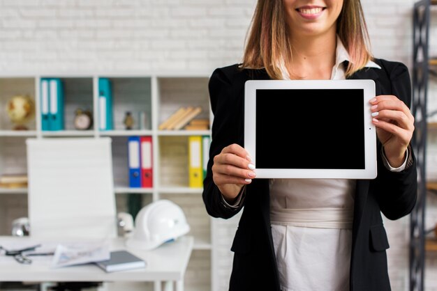 Mujer sonriente que sostiene una maqueta de la tableta