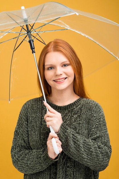 Foto gratuita mujer sonriente que sostiene el paraguas transparente