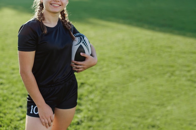 Mujer sonriente que sostiene una pelota de rugby