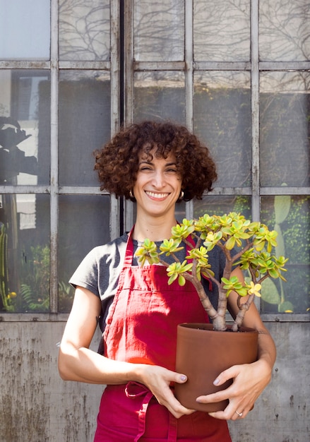 Foto gratuita mujer sonriente que sostiene una planta hermosa