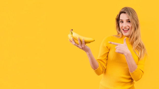 Mujer sonriente que sostiene plátanos