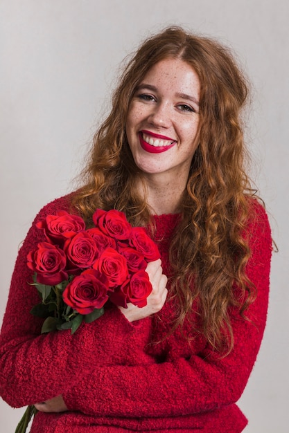 Mujer sonriente que sostiene un ramo de rosas