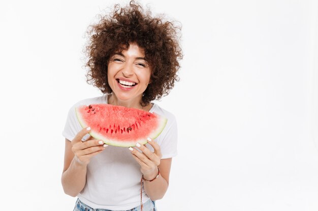 Mujer sonriente que sostiene la rebanada de una sandía y riendo