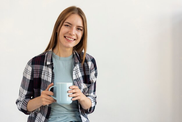 Mujer sonriente que sostiene una taza de café con espacio de copia