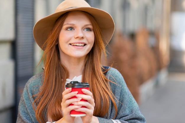 Mujer sonriente que sostiene la taza de café