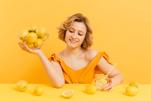 Mujer sonriente que sostiene el tazón de fuente con los limones