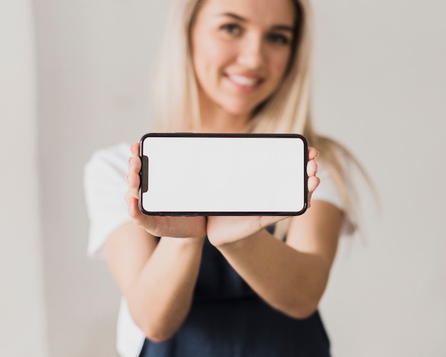 Mujer sonriente que sostiene el teléfono con maqueta