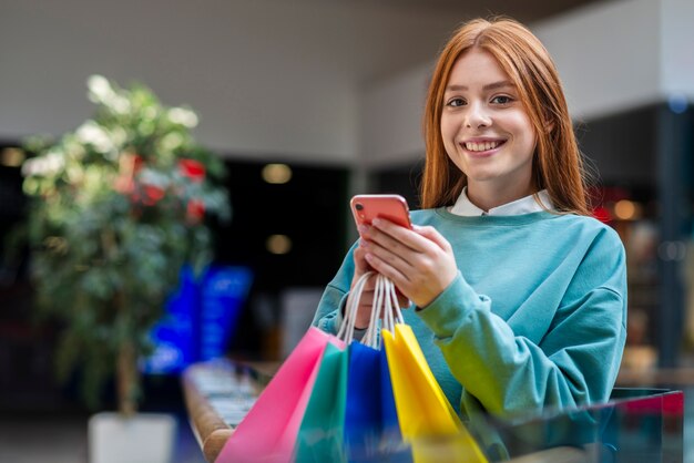 Mujer sonriente que sostiene el teléfono y que mira al fotógrafo