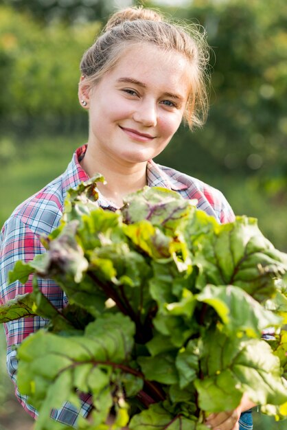 Mujer sonriente que sostiene verduras