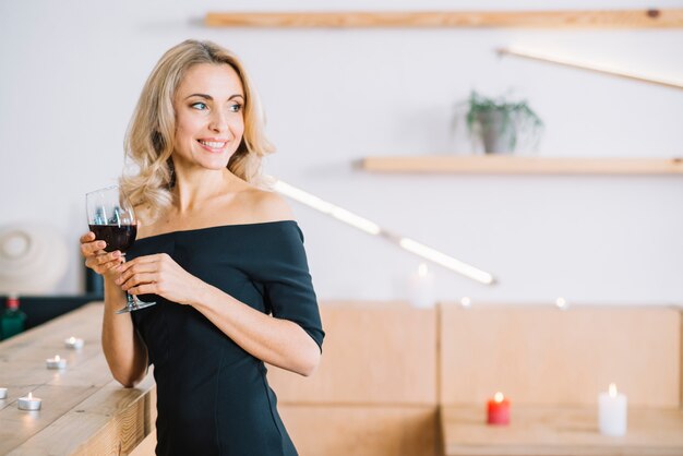 Mujer sonriente que sostiene el vino de cristal