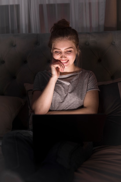 Mujer sonriente que trabaja en la computadora portátil