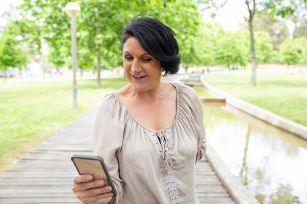 Mujer sonriente que usa smartphone al aire libre