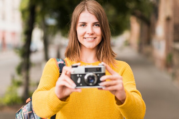 Mujer sonriente que viaja con cámara