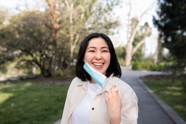 Foto gratuita mujer sonriente quitándose la máscara de tiro medio