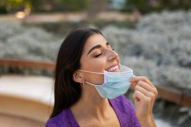 Mujer sonriente quitándose la máscara de la vista lateral