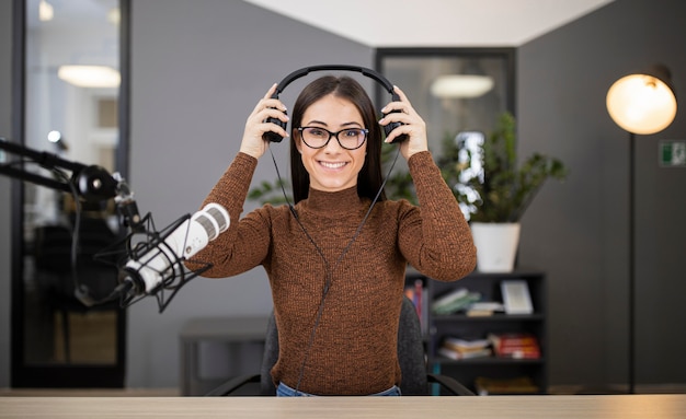 Mujer sonriente en la radio con micrófono y auriculares
