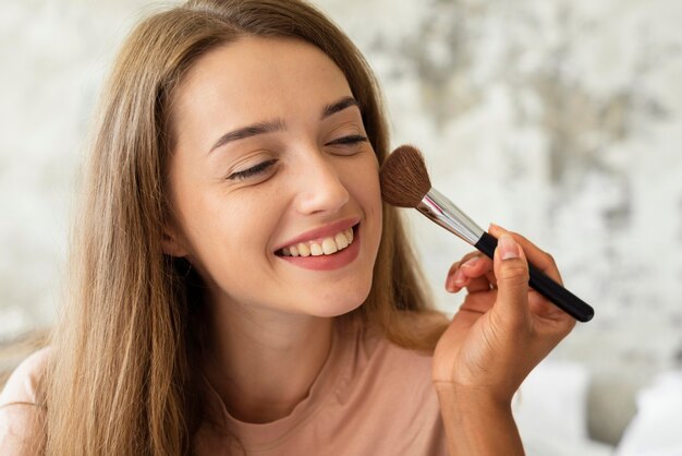 Mujer sonriente recibiendo ayuda con el maquillaje de un amigo